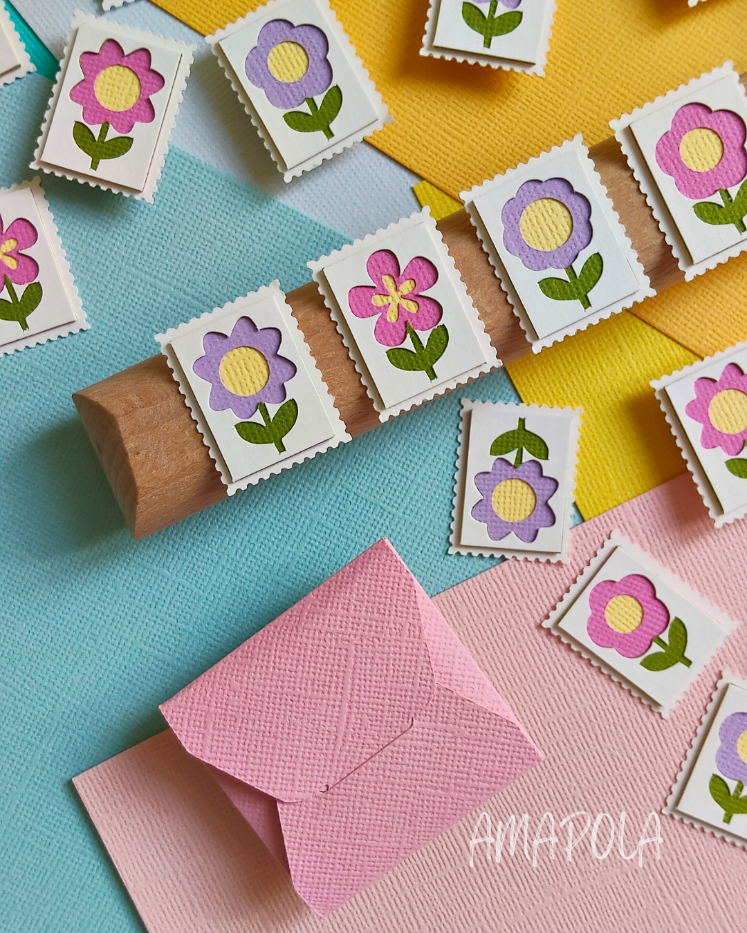 P’tits Timbres artisanaux en papier représentant des fleurs roses et violettes, regroupés en deux sets de quatre timbres chacun, réalisés en relief avec plusieurs couches découpées à la main.