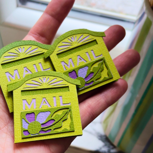 Boîte à Vœux faite main, dans les tons verts et violets, s'ouvrant comme une carte. Contient une enveloppe et trois petits papiers pour personnaliser ton message de vœux pour 2026.