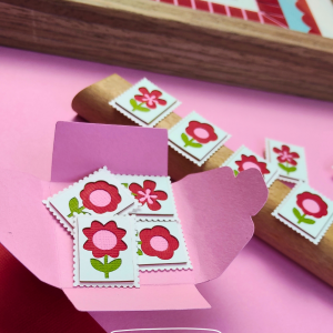 Quatre mini timbres fleurs rouges en papier découpé à la main présentés dans un cadre décoratif
