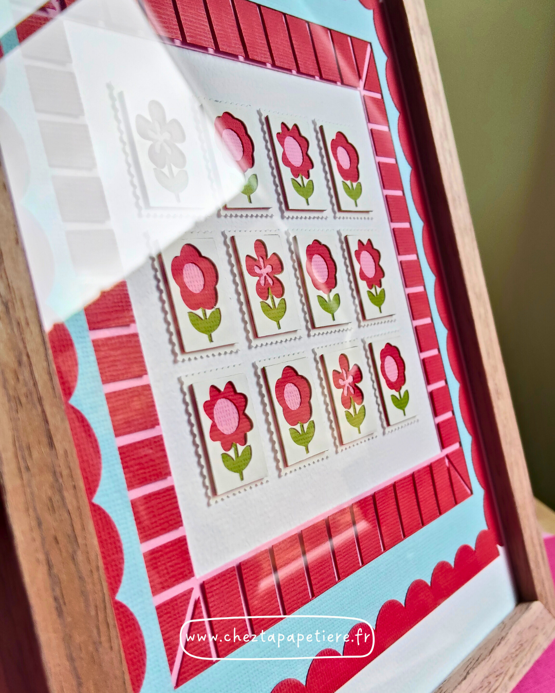 Quatre mini timbres fleurs rouges en papier découpé à la main présentés dans un cadre décoratif