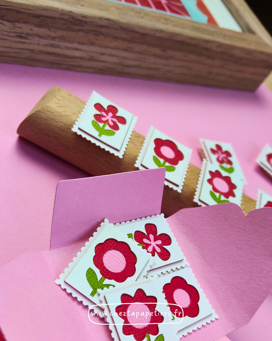 Quatre mini timbres fleurs rouges en papier découpé à la main présentés dans un cadre décoratif