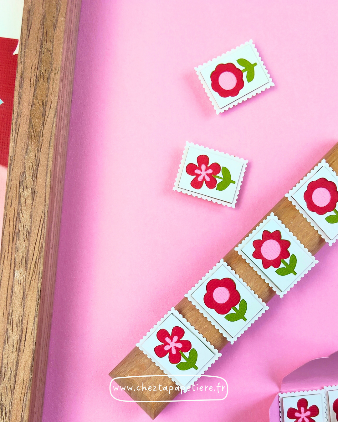 Quatre mini timbres fleurs rouges en papier découpé à la main présentés dans un cadre décoratif