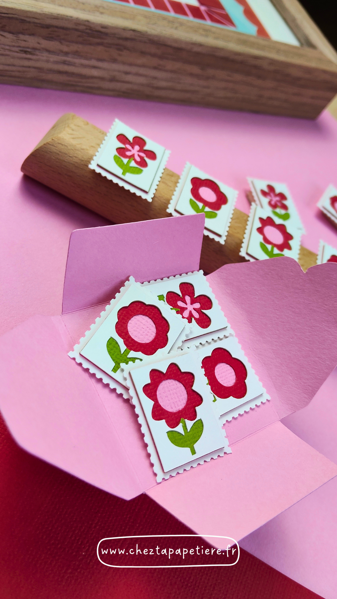 Quatre mini timbres fleurs rouges en papier découpé à la main présentés dans un cadre décoratif